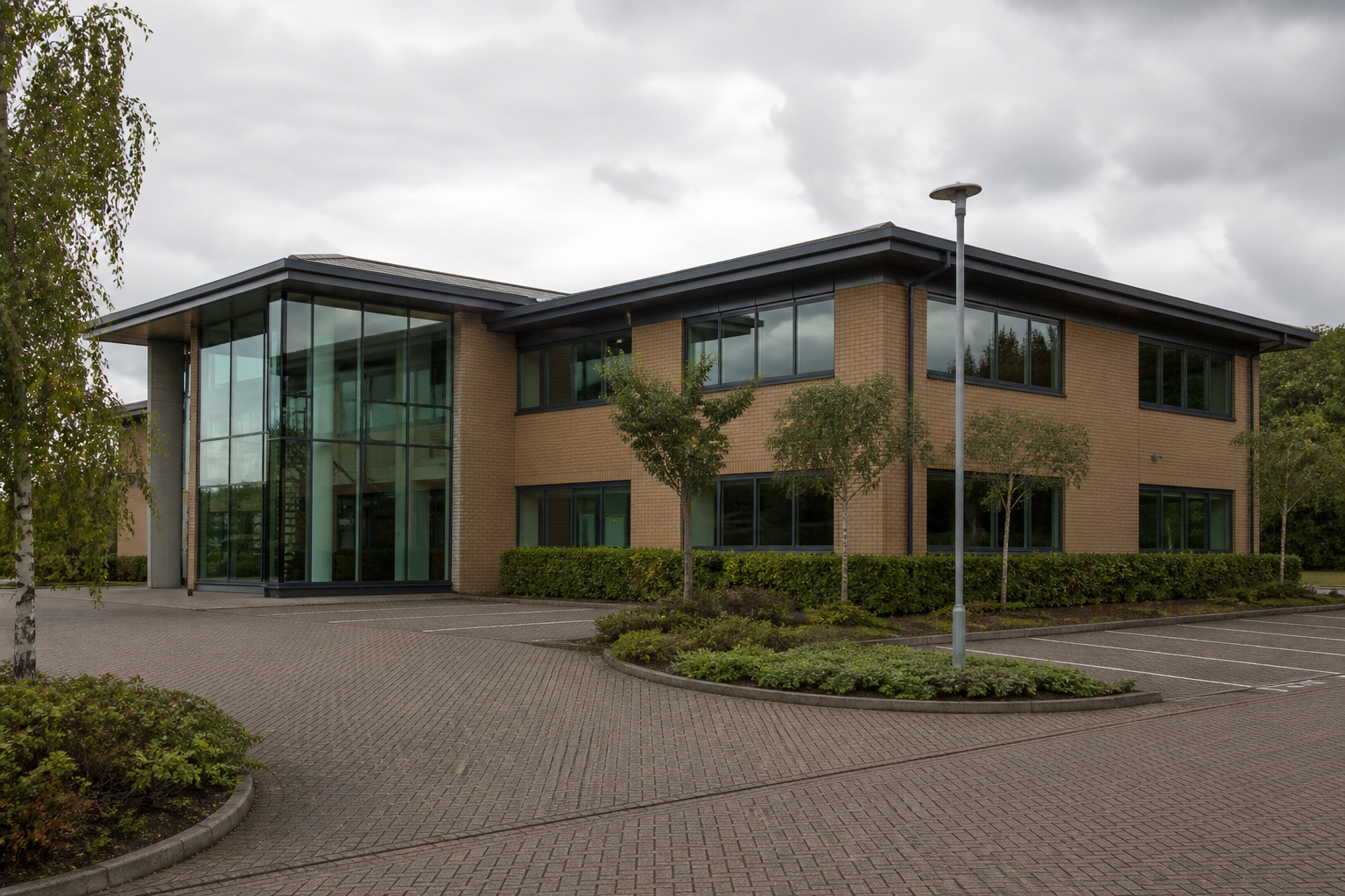 A modern English business-park office building in a suburban setting, with no readable signs