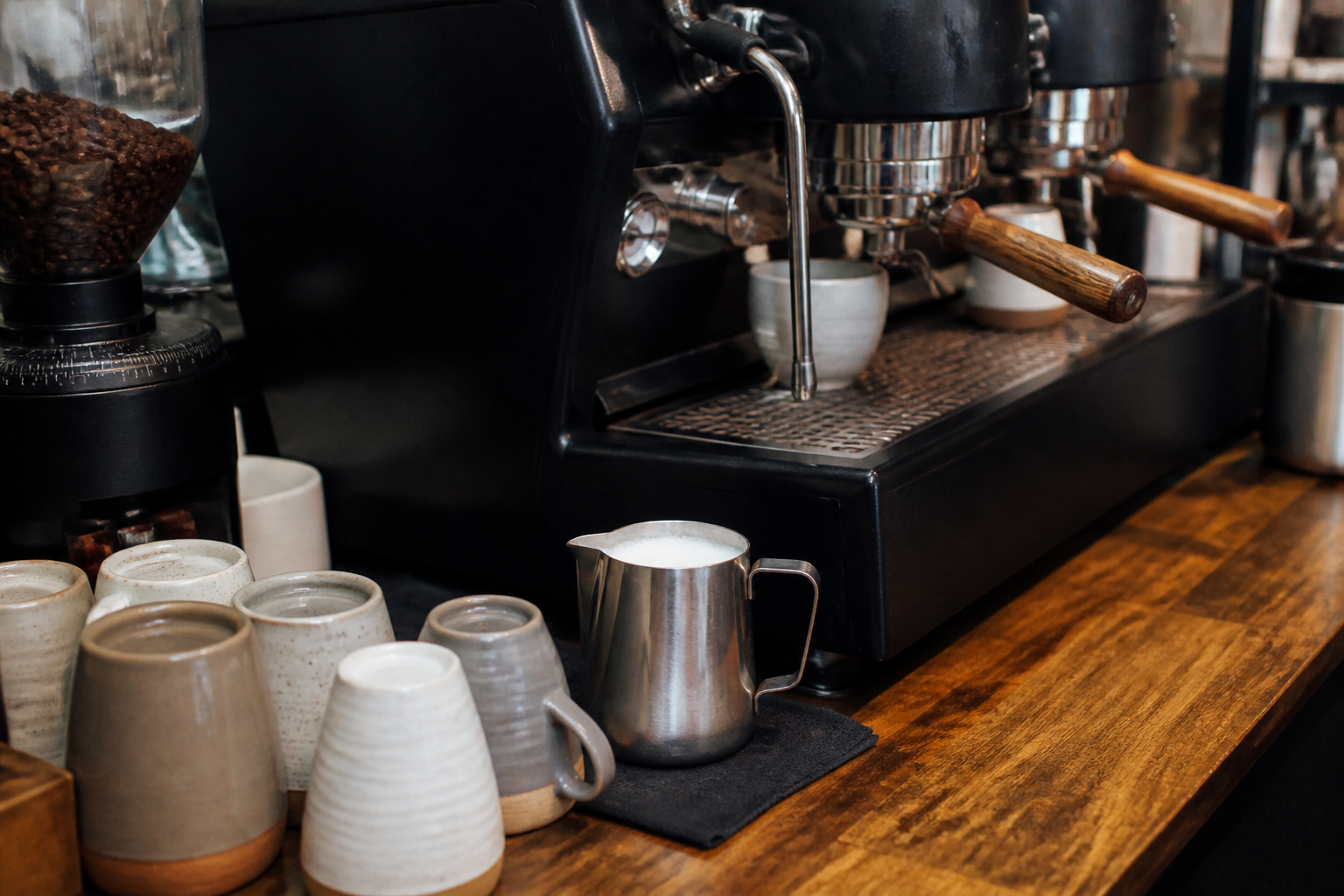Ceramic cups and steamed milk on a cafe counter, with no brand logos
