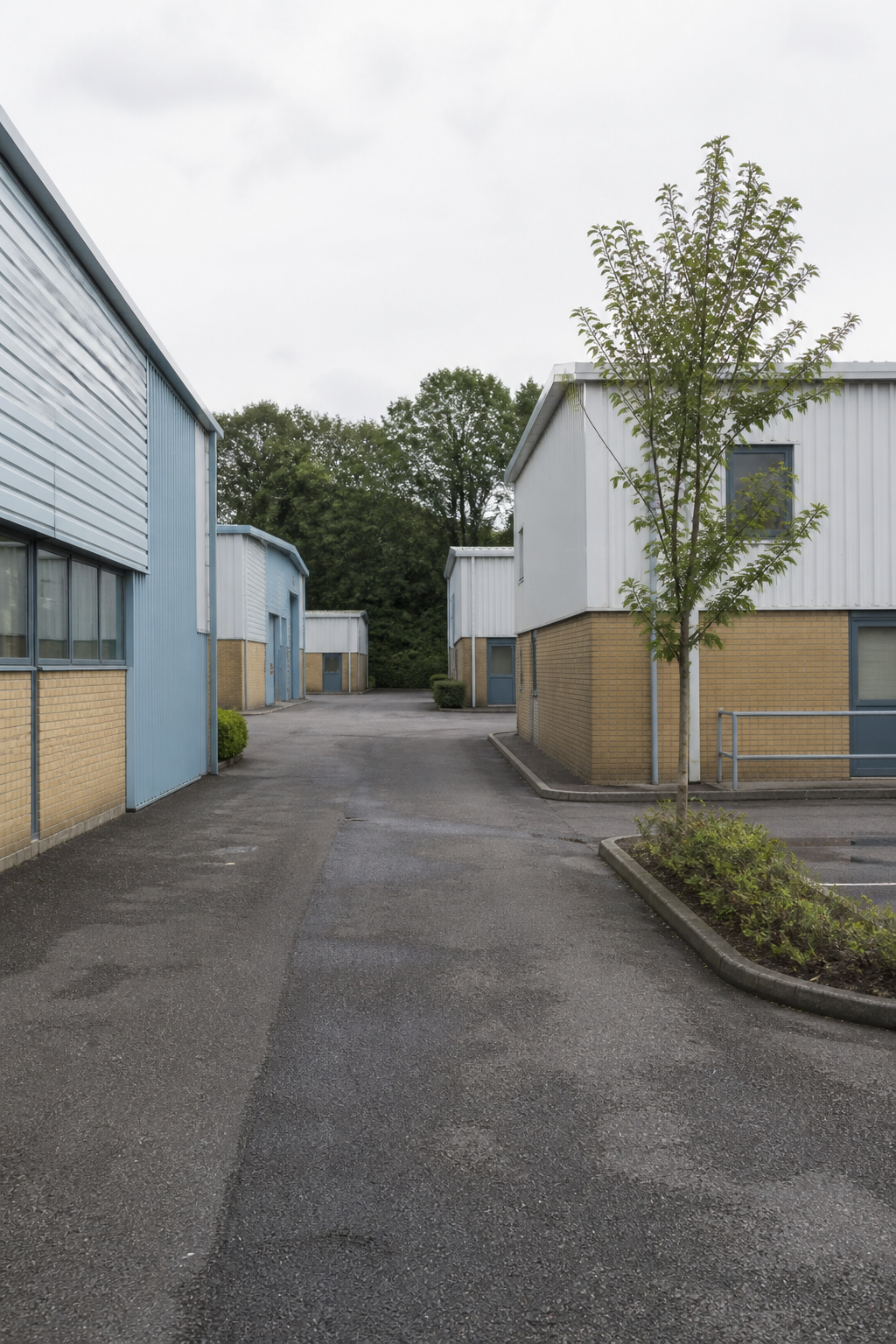 A quiet English industrial close between low business-park units, with no signs