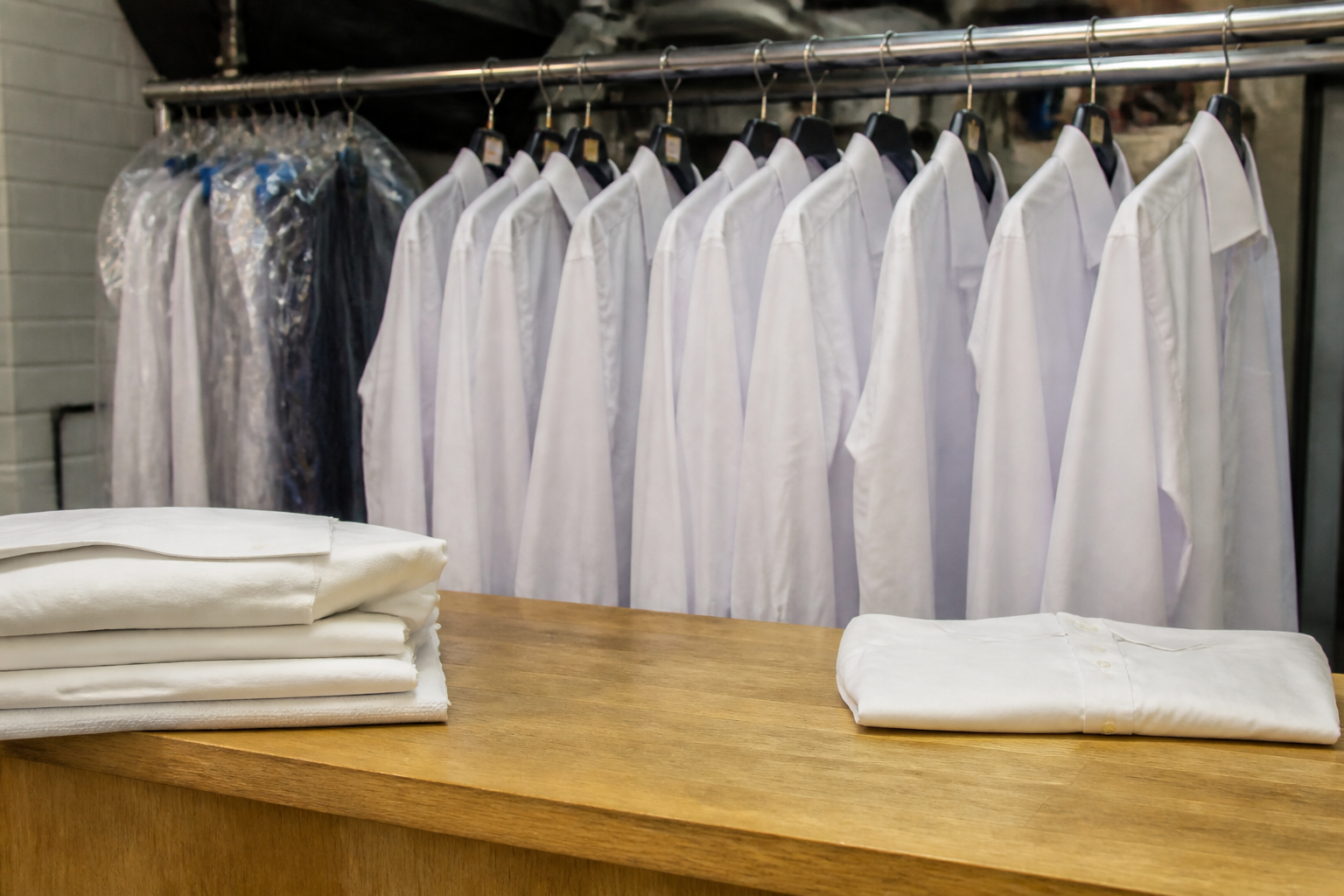 Pressed shirts and folded linen on a laundry counter, with no price tickets