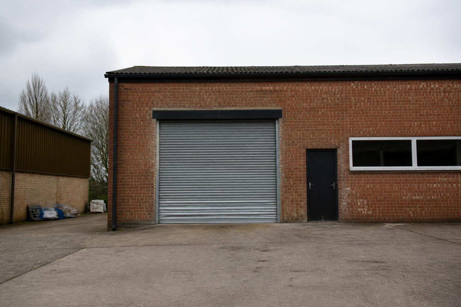 A small British industrial unit with a roller shutter on a trading estate, with no readable signs