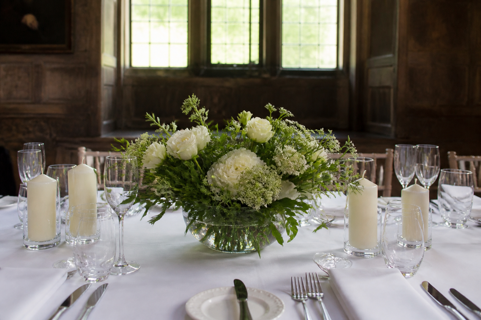 A wedding table centrepiece of white and green flowers on linen, with no place cards
